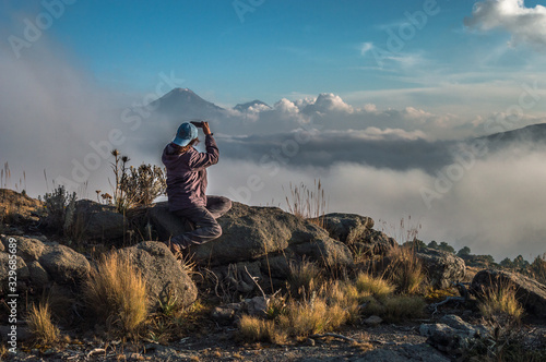 Ella tomando una foto con el celular en las montañas al atardecer.