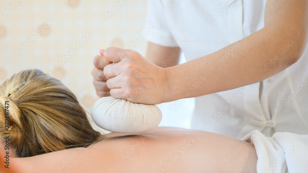 Health care and thai massage. Beautiful woman getting thai herbal ball compress back and shoulder massage in spa salon Health care and thai massage. Beautiful woman getting thai herbal ball compress back and shoulder massage in spa salon