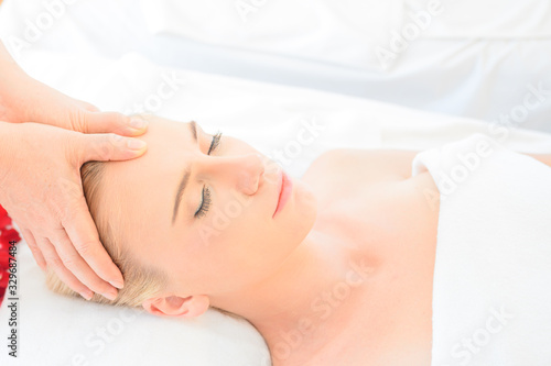 Beautiful woman receiving head and facial massage in spa salon. Concept of body health care and traditional thai massage relax
