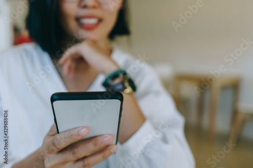 Woman feel happy and smile while using smartphone to do work business, social network, communication in public cafe work space.