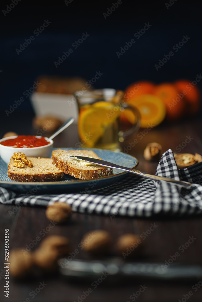 Breakfast, bread and butter with jam and tea on a dark wooden background