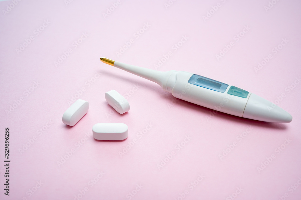 Digital thermometer and white pills isolated on pink background. Digital thermometer and white pills isolated on pink background.