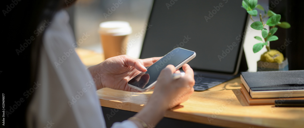 Cropped shot of university student take short break with smartphone on wooden counter bar