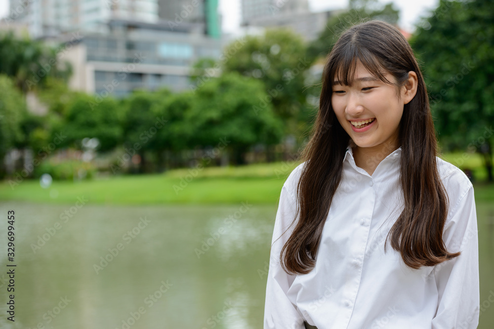 Happy young beautiful Asian teenage girl thinking at the park Happy young beautiful Asian teenage girl thinking at the park