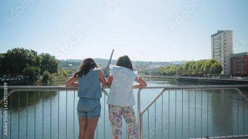 Two girls at a bridge in Pontevedra talking at a sunny summer day photo