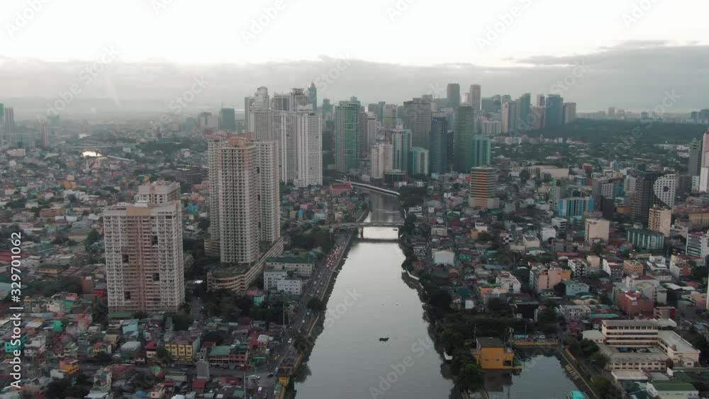 Aerial drone shot showing Makati City with a skyscraper reflection in the pasig river of Manila, Philippines while sunrise