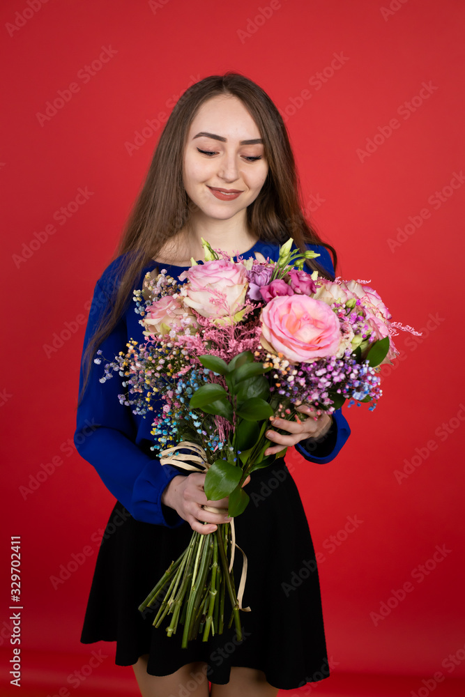 a young girl holding a bouquet of flowers, she smiles, stands on a red background a young girl holding a bouquet of flowers, she smiles, stands on a red background
