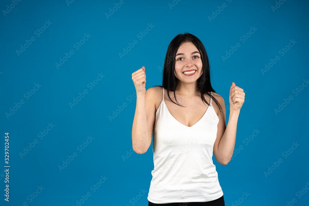 Front view of happy girl showing yes gesture isolated on blue background Front view of happy girl showing yes gesture isolated on blue background