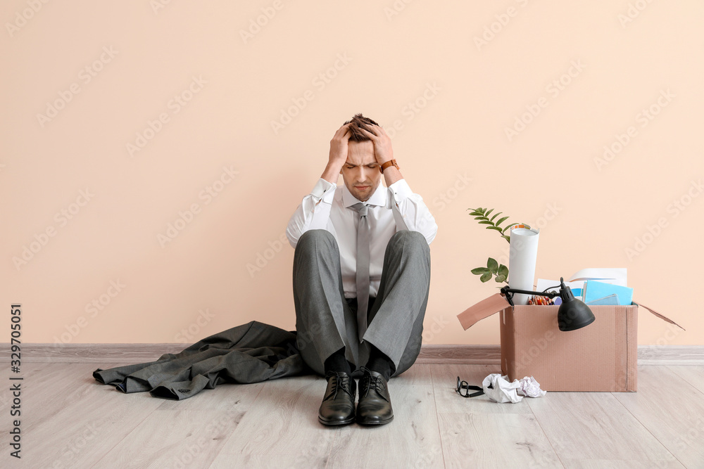 Sad fired man sitting near color wall Sad fired man sitting near color wall