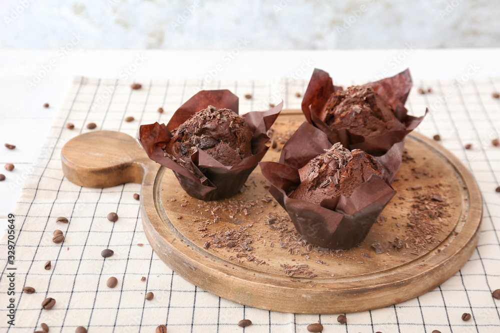 Board with tasty chocolate muffins on table Board with tasty chocolate muffins on table