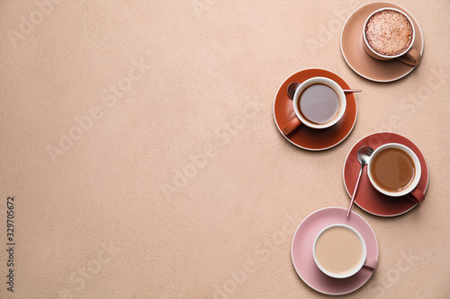 Cups of different coffee on color background