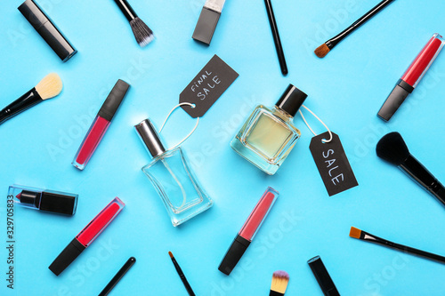 Bottles of perfumes with makeup cosmetics on color background