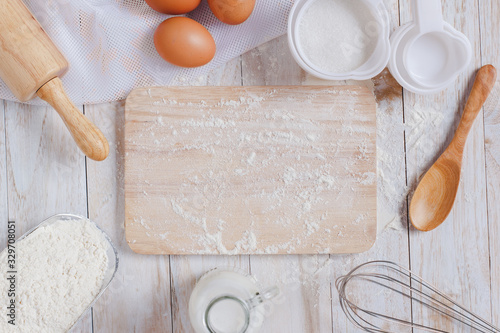 Homemade Dough Recipe (Eggs, flour, milk, sugar) and wooden kneading dough on a wooden table, view from above