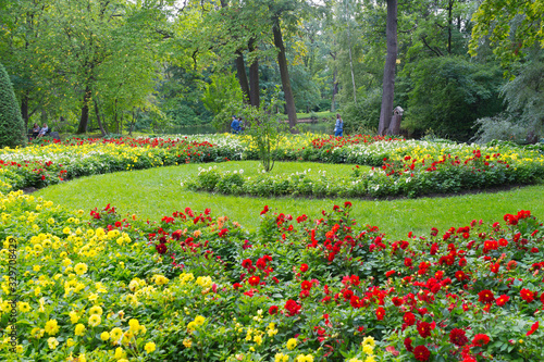 Saint Petersburg. People enjoy a stroll through a beautiful city park with magnificent flower beds and relax on benches in the shade of green trees on Elagin Island