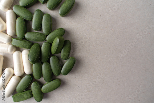 green chlorella pills and white pills on a gray background. nutritional supplements for a healthy diet photo