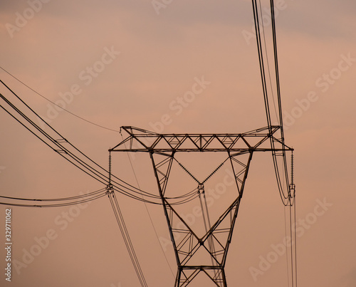 Overhead power lines silhouetted against a late afternoon orange skyline image for background use with copy space