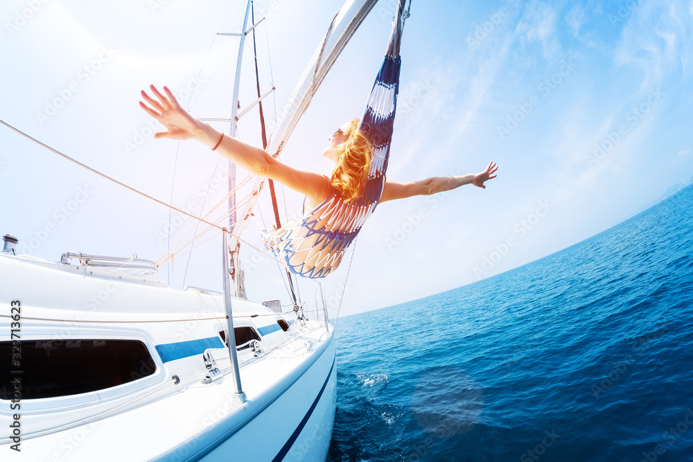 Young woman enjoys tropical sailing in the hammock set on the yacht - obrazy, fototapety, plakaty 