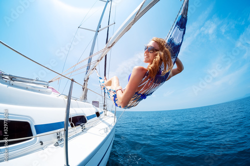 Young woman enjoys tropical sailing in the hammock set on the yacht © Dudarev Mikhail