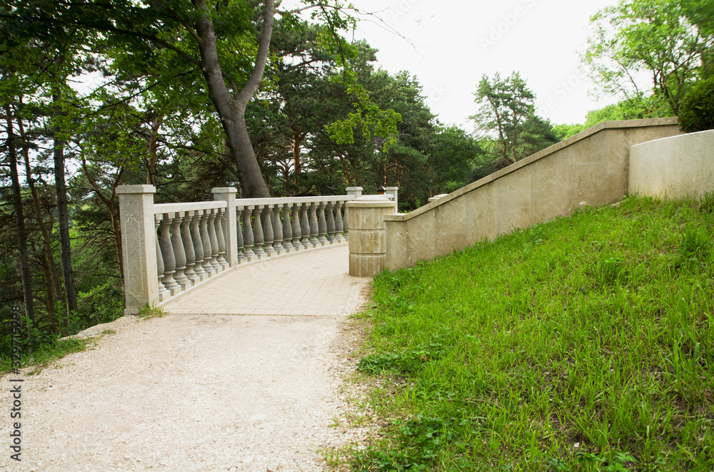 Stone Park path and railing surrounded by trees and grass