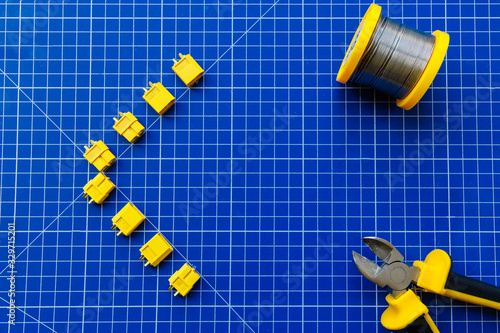 Blue rug for cutting. The connectors XT-60 are laid out on the mat. In one corner lies a solder coil. In another corner are yellow-black nippers. Presentation blank