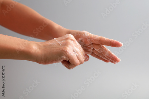 Female washing hand with soap on grey background. Good personal hygiene practices.