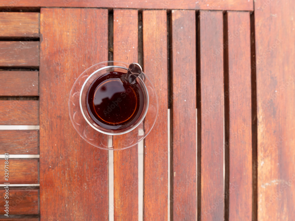 Turkish black tea glass with teaspoon on the wooden table. Turkish black tea glass with teaspoon on the wooden table.