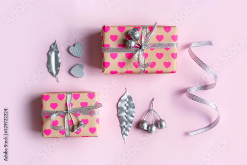 Gift flat-lay on a pink background. Gifts are wrapped in heart pattern paper with silver ribbon decorated by silver hearts, Australian eucalyptus leaves and gum nuts painted silver.