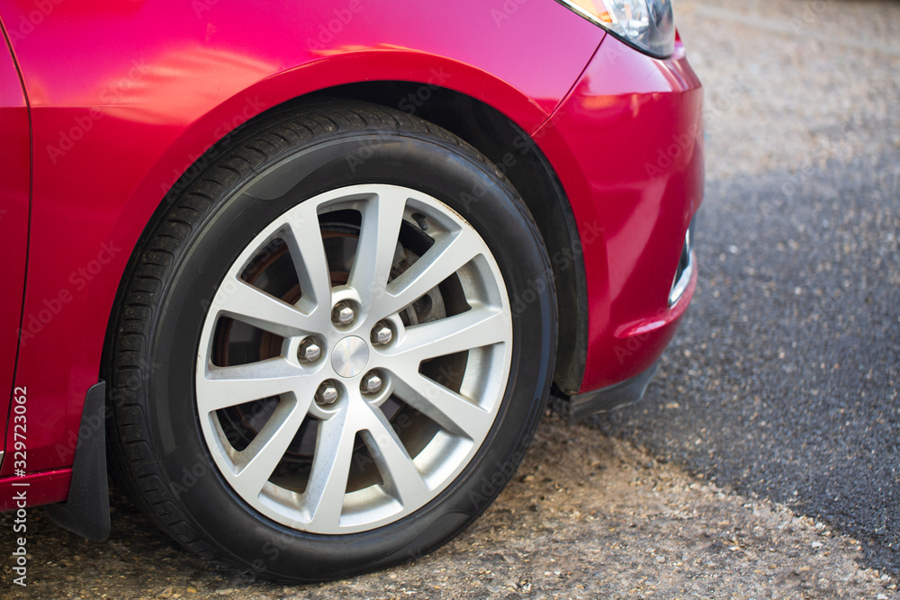Car on the Parking Spot. Alloy Wheel Closeup Photo. Lower Ground Level. Transportation and Automotive Theme. Car on the Parking Spot. Alloy Wheel Closeup Photo. Lower Ground Level. Transportation and Automotive Theme.