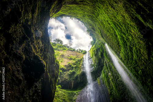 Beautiful view of Madakaripura waterfall with green moss and blue sky in Java  Indonesia.