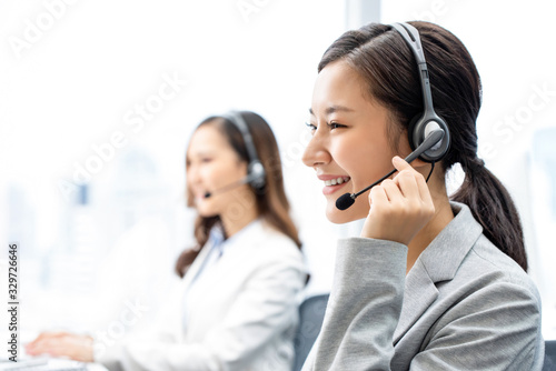 Smiling telemarketing Asian woman working in call center office photo