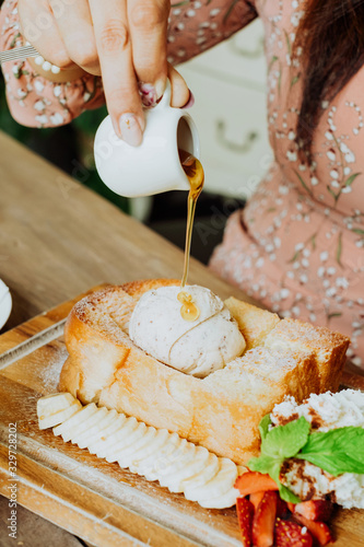 Hand is pouring honey syrup on the sweet toast , Honey toast and ice cream.