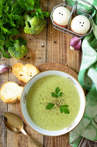 Vegetarian dish. Delicious broccoli cream soup served with garlic croutons on a rustic table. Top view flat lay background. Copy space.