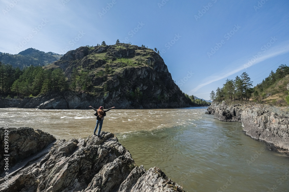 Portrait of a woman on the edge of the cliff against the Altai mountains.
