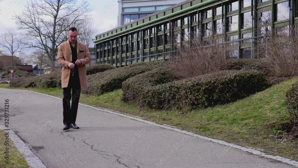 pretty brunette in a beige coat walks along the sidewalk pretty brunette in a beige coat walks along the sidewalk