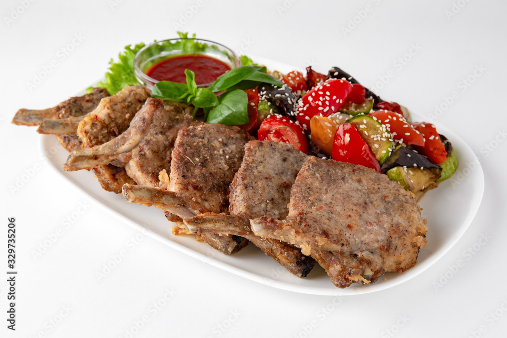Rack of lamb, or rabbit shoulder blade, pork ribs with grilled vegetables. Banquet festive dishes. Gourmet restaurant menu. White background. Rack of lamb, or rabbit shoulder blade, pork ribs with grilled vegetables. Banquet festive dishes. Gourmet restaurant menu. White background.