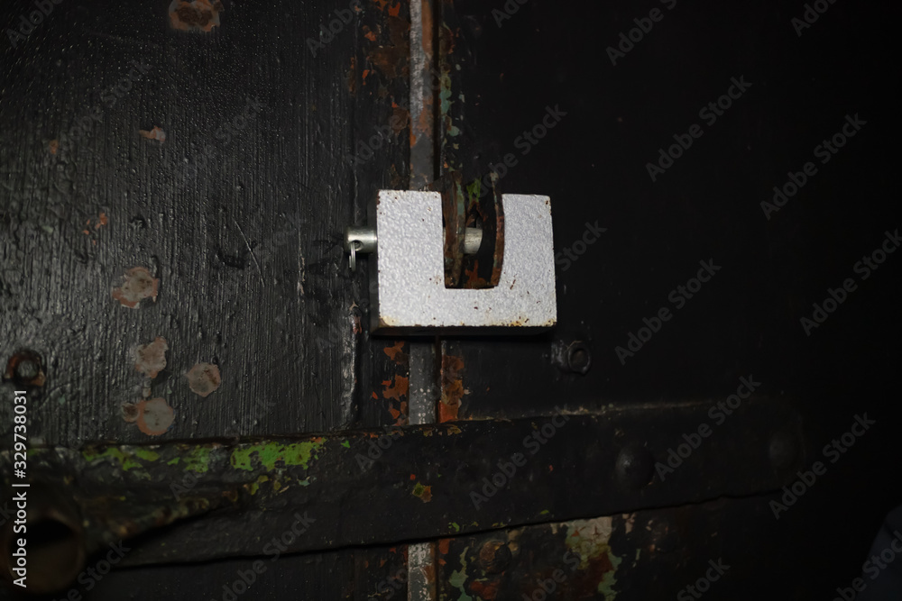 Steel lock hanging on the door of an old garage in the dark, copy space Steel lock hanging on the door of an old garage in the dark, copy space