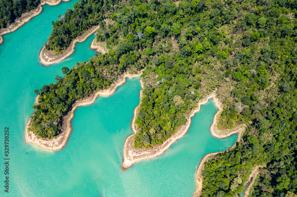 Aerial view looking downwards onto tiny islands and fingers of tropical rainforest covered land in a huge lake