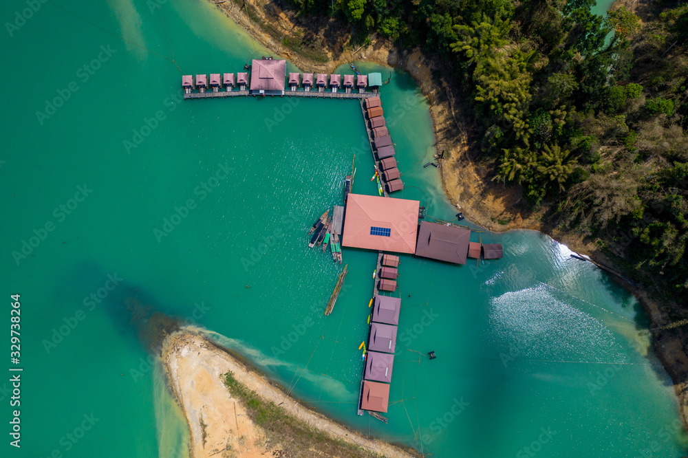 Aerial drone view of a floating wooden rafthouse surrounded by huge cliffs and tropical jungle (Khao Sok)