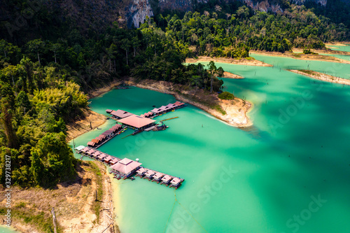 Aerial drone view of a floating wooden rafthouse surrounded by huge cliffs and tropical jungle (Khao Sok)