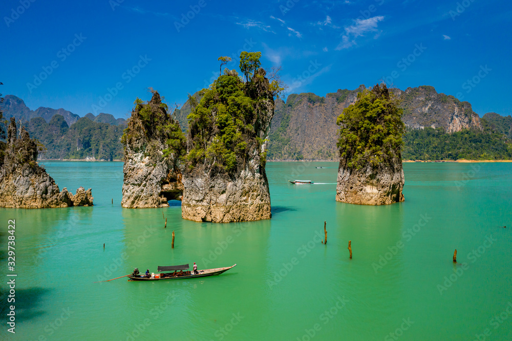 Fototapeta premium Aerial drone view of longtail boats around spectacular limestone fingers and karsts on a huge lake surrounded by jungle