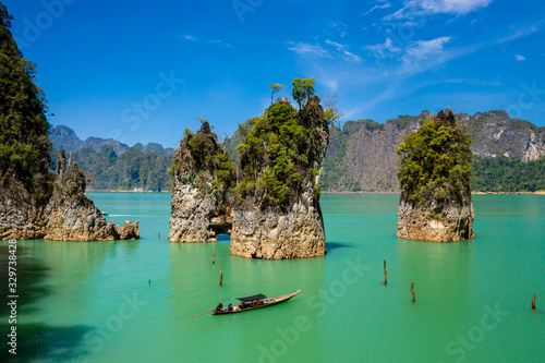 Aerial drone view of longtail boats around spectacular limestone fingers and karsts on a huge lake surrounded by jungle