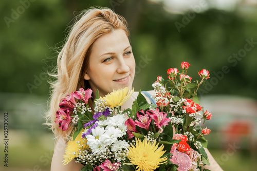 beautiful woman with a bouquet of flowers on a blurred background of the Park © yurolaitsalbert