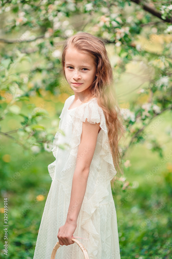 Adorable little girl in blooming apple garden on beautiful spring day Adorable little girl in blooming apple garden on beautiful spring day