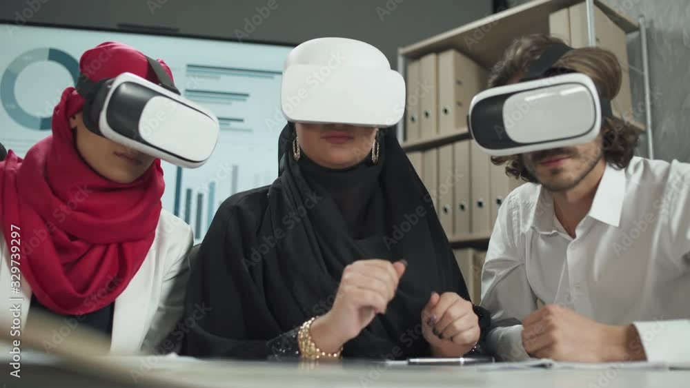 international business meeting, man and two muslim woman in virtual reality glasses, communicate and discuss financial ideas, cyberspace. international business meeting, man and two muslim woman in virtual reality glasses, communicate and discuss financial ideas, cyberspace.