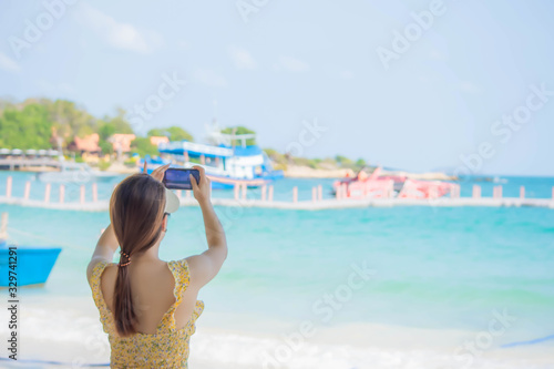 Women are taking photos with the phone on the beach Background Sea. January 25, 2020