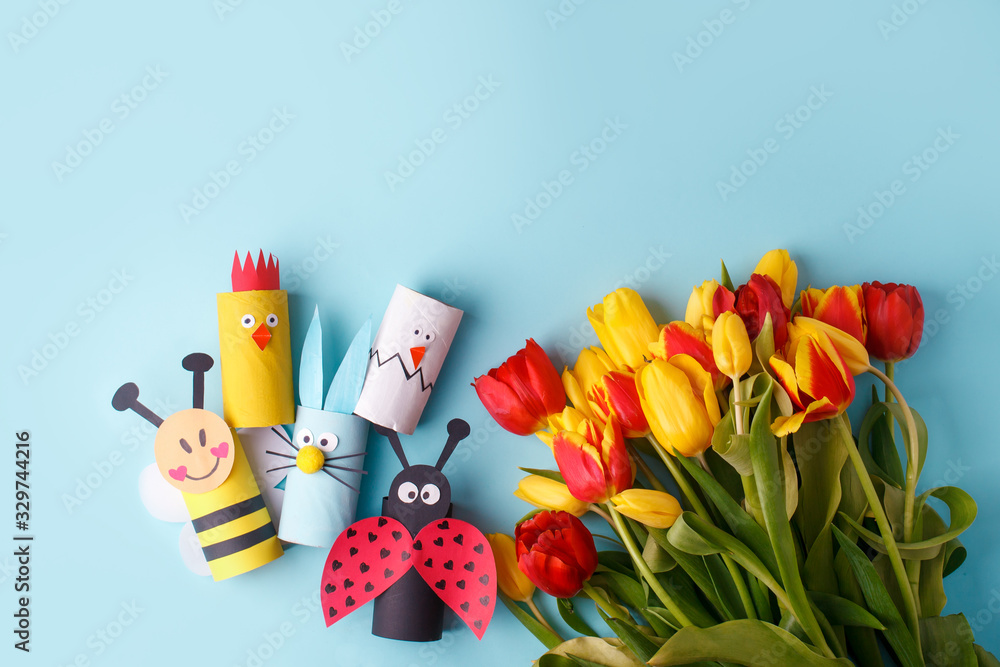 Springtime season greeting card - happy easter concept - multicolored tulips, eggs, decor from toilet roll tube on blue background, copy space, celebrate banner
