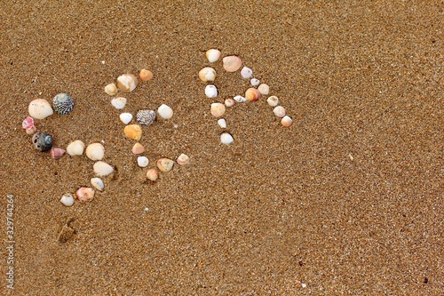 Sand sea coast with inscription "sea" made by shells. Concept of vacation, travel, summer, nature.