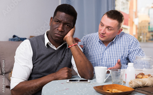 Unhappy male after conflict, friend tries reconcile