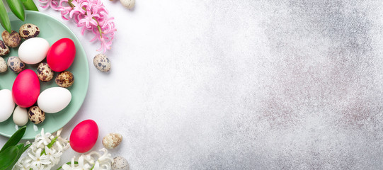 Easter composition. Green mint plate, easter eggs, pink and white hyacinth on stone background. Horizontal banner. Copy space for text