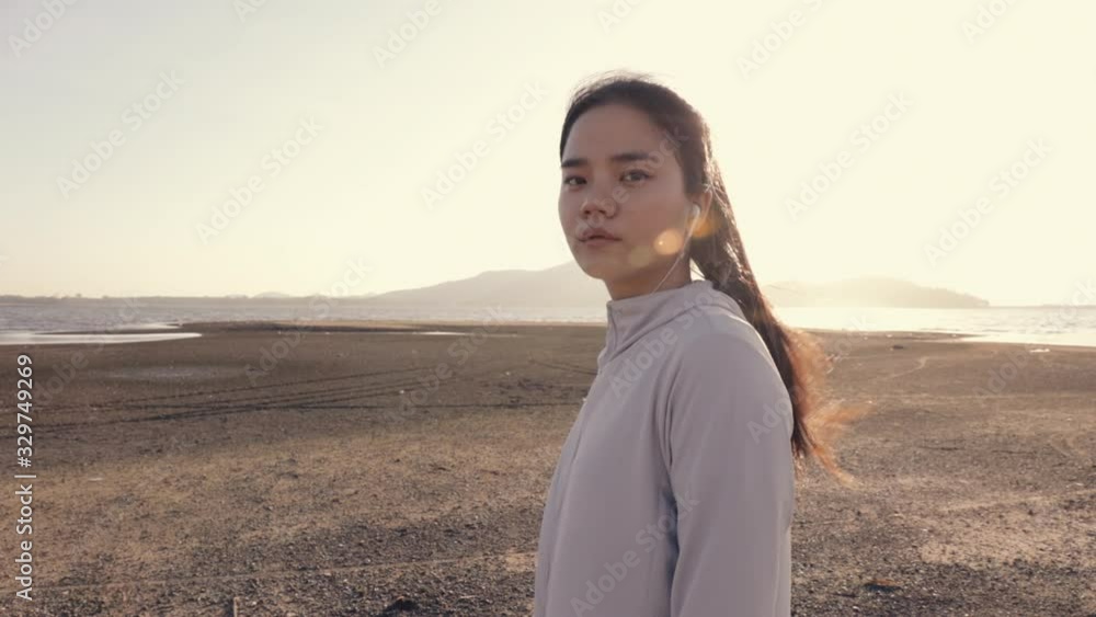 Attractive young asian woman athletic looking at camera while standing on the beach last beautiful sunset. Healthcare lifestyle concept. Attractive young asian woman athletic looking at camera while standing on the beach last beautiful sunset. Healthcare lifestyle concept.
